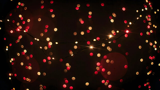 Festive string lights with soft red and warm white bokeh circles glowing against a dark background, for holiday celebration atmosphere