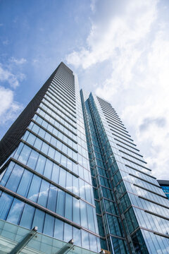 Towering corporate skyscraper photographed from street level in Brussels, showcasing elegant curtain wall glazing, soaring proportions and modern European office architecture with spacious sky.