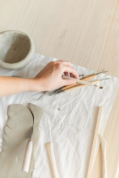 Women artist pottery shaping clay on a worktable with tools and cloth