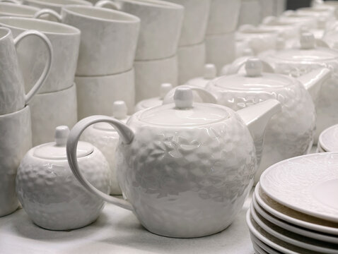 White porcelain mini teapots sugar bowls cups and plates forming basic kitchenware set in store shelf arrangement designed for practical everyday tableware use and retail sale