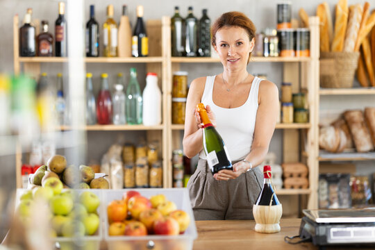 Female salesperson offers to buy bottle of wine in liquor department of a grocery supermarket