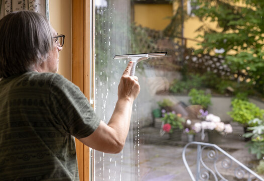 Mature man clean apartment window with squeegee