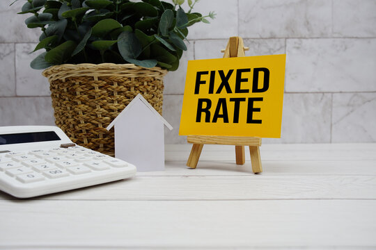 Fixed Rate text with house model and calculator on wooden background