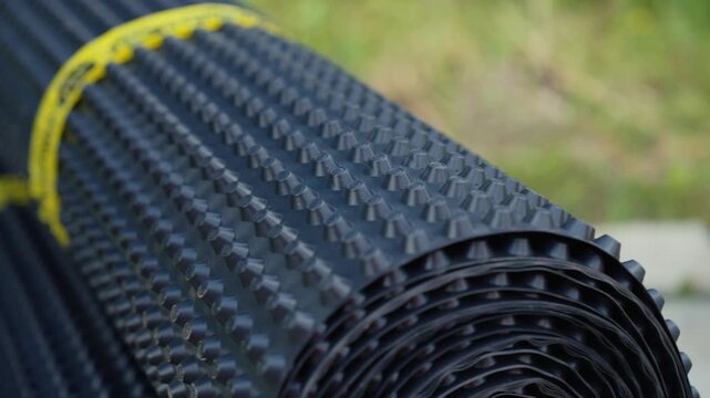 Close up view of a studded drainage membrane roll used for foundation waterproofing and protection, showcasing the detailed texture of the high density polyethylene material for construction