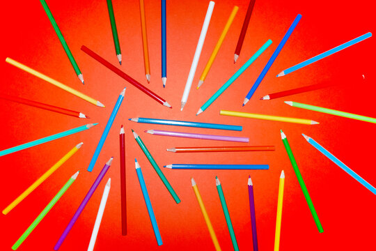 Colorful pencils form abstract pattern on orange background