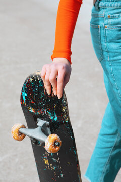 Close-up of person holding skateboard with donut wheels