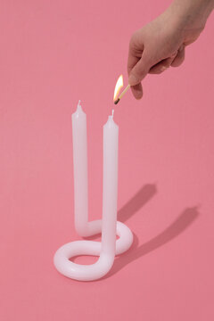 Hand lighting contemporary twisted white candle on pink