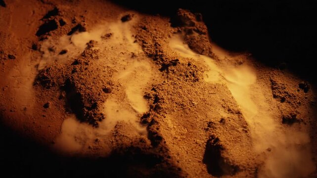 Mysterious orange sand with strange white smoke rising from the ground, creating an atmospheric and alien landscape with dark shadows, suggesting a volcanic or geothermal activity on another planet