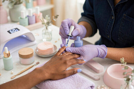 Professional Manicurist Applying Light Blue Gel Polish to Client's Nails in Bright Beauty Salon