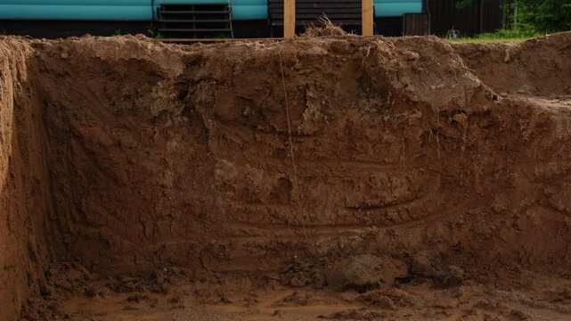 Earthmoving machinery digging a deep trench for a building foundation or pipeline installation on a construction site, preparing the ground for future development and infrastructure projects