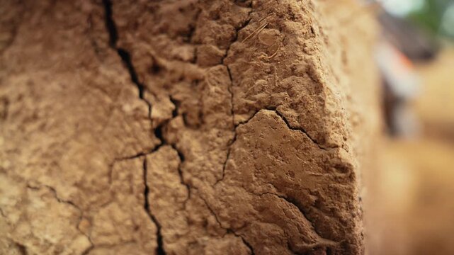 Extreme close up shot capturing the weathered texture of a traditional earthen building, showing deep cracks and rough surfaces that reveal the effects of time and erosion on the structure