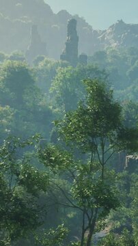 Tall trees surround ancient ruins on a hillside. The sun shines brightly, highlighting the greenery and the stone structures that stand tall in the distance.