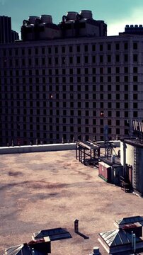 A rooftop view shows empty spaces and construction structures. Nearby buildings stand tall against a clear sky. The area is quiet with no visible people or movement.