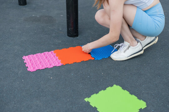 A woman with cerebral palsy walks on sensory mats. Rehabilitation