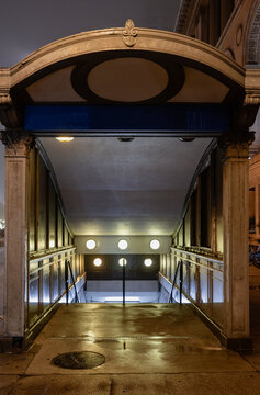 A beautifully designed subway entrance shrouded in mist, featuring glowing round lights that create a mysterious and inviting atmosphere in the city at night.