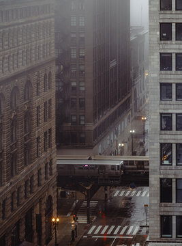 A serene urban scene depicting a train passing through a foggy cityscape, encapsulating the dynamic yet tranquil essence of city life during rainy weather.