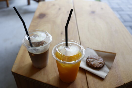 カフェ店内のドリンクとクッキー。オレンジジュースとコーヒー。木製テーブル