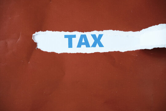 Torn paper with TAX written on the back. Tax payment time concept