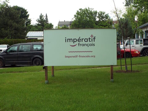 Gatineau, Quebec, Canada &ndash; June 11, 2026: A light green "Imperatif francais" organization sign with website details stands on a grassy lawn beside a street on Chem. Eardley.
