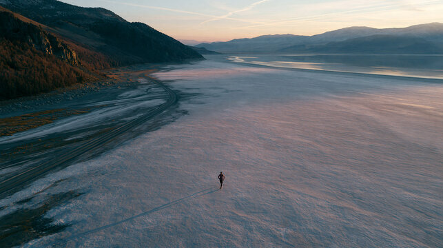 Solitary Figure Walking Across Frozen Lake at Dusk