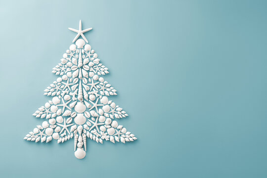 Seashell Christmas tree with starfish on light blue background. Tropical Christmas, coastal summer holiday, beach decor, flat lay image with copy space