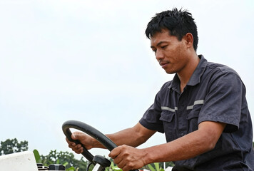 Obraz premium Asian farmer operating agricultural machinery, rural farming and sustainable agriculture concept, outdoor work and cultivation