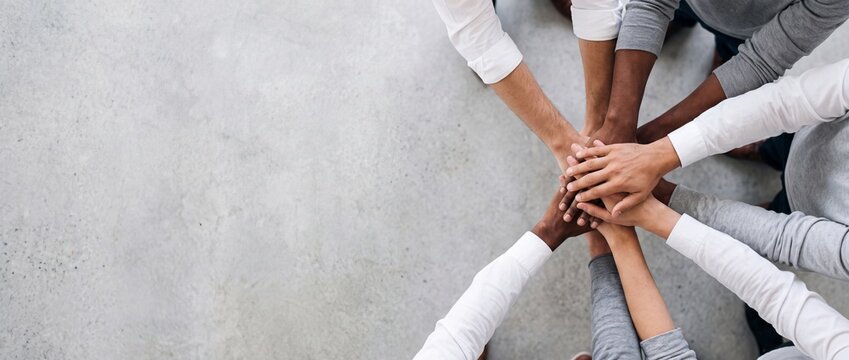 Diverse group stacking hands together. Team building concept showing unity and cooperation.