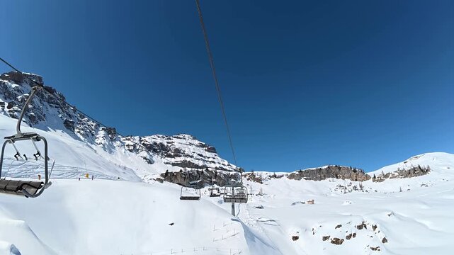 Person riding a chairlift over snowy slopes in the dolomites
