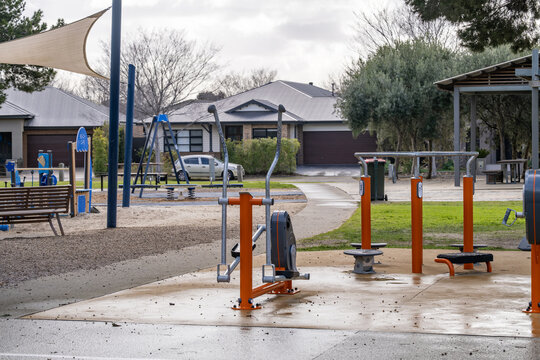 An outdoor fitness station and children's playground in a suburban park, featuring exercise and play equipment.  Residential homes surround the community recreational area Melbourne Australia