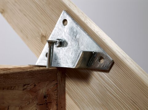 Stair stringer connector bracket fastened to wood framing at base of stair stringers