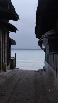 Sandy path between beach huts leading to the ocean