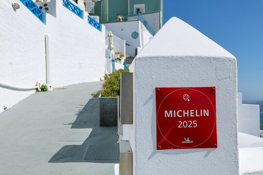 A Michelin 2025 plaque displayed on a whitewashed building in Santorini, Greece, marking culinary excellence amid the island&rsquo;s iconic Mediterranean architecture.
