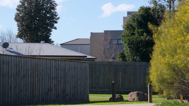 Timber paling fence line bordering a suburban residential area in Melton, Melbourne, Australia. Modern houses rise behind the perimeter fencing,&nbsp;walking path in a residential neighbourhood