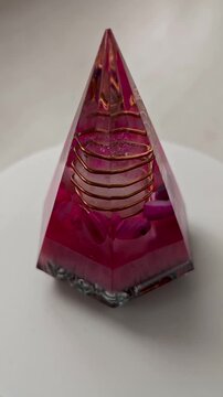 Vertical Rotating Pink and Red Octagonal Orgone Pyramid with Quartz Crystal, Handmade Epoxy Resin Sculpture, 360 Degree Crystal Art Video, Sacred Geometry Decor on White Background