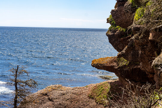 Gaspesie, Quebec, 15 July 2026 : A rugged coastal cliff overlooks the vast, sparkling blue ocean under a clear sky.