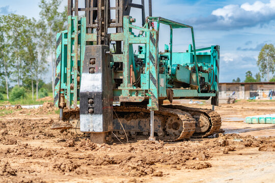 Green pile driving rig machine working on a construction site for ground foundation work.