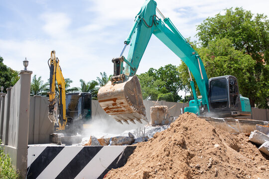 Two excavators working together to demolish concrete structure at construction site