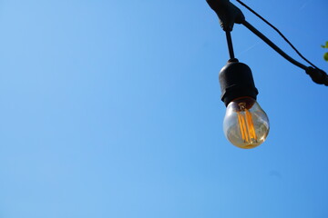 Close Up of Vintage Edison Light Bulb on Blue Sky © Aisyah Faiha