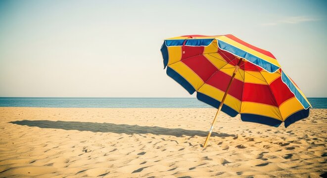 A nostalgic striped parasol sits on golden sand by the sea, showcasing a warm vintage film aesthetic with soft shadows and faded tones, water, sunshade, warmth