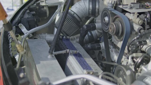 Action close-up shot of a spray nozzle rinsing down the front-mounted intercooler and cooling assembly in the engine bay of a tuned race car.