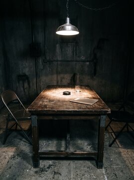 Interrogation room with wooden table and single light bulb