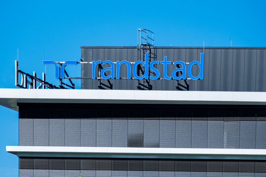 Randstad logo modern office building, Dutch HR agency, staffing solutions, temporary work, trust uncertainty recruitment, corporate workforce mobility post-pandemic Europe and Asia, Eschborn, GERMANY