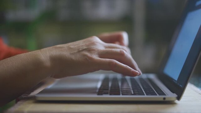 A woman types on a laptop, focusing intently. The woman s hands move quickly over the keyboard, indicating productivity and concentration.
