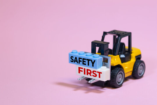 Toy forklift carrying a safety first message on building blocks