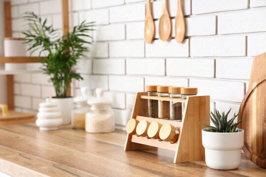 Modern kitchen interior with wooden countertop, white brick wall, spice rack, and potted plants for home decor