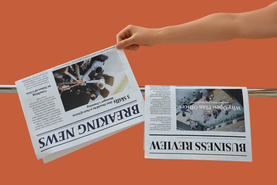 Hand holding a newspaper with breaking news and business review headlines on an orange background, the newspaper features articles on topics such as "coaching in times of crisis