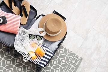 Fototapeta na wymiar Open suitcase packed with summer vacation essentials including a straw hat, flip-flops, and sunscreen, ready for travel
