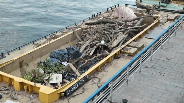 Barge on river carrying collected trash and debris, pollution problem solution
