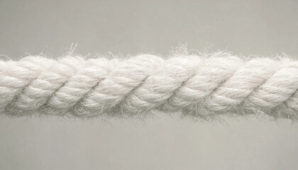 Close up view of a thick white twisted cotton rope showing detailed fibers and texture against a neutral light grey background surface © Djjsjsk