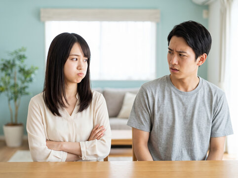 部屋のテーブルで腕を組み拗ねた顔をする若い女性